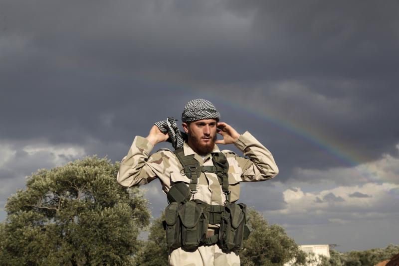 A rainbow is seen over an Islamic Ahrar al-Sham fighter on the frontline of Idlib city in northern Syria, where they announced a battle to liberate the city from forces loyal to Syria's president Bashar Al-Assad, March 20, 2015.