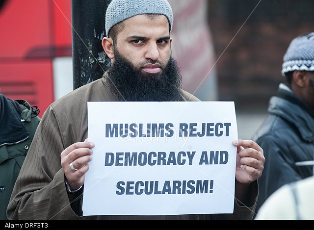 London, UK. 24th January 2014. Abu Walaa, founder of Muslim Prisoners,holds a placard reading "Muslims reject democracy and secularism!" outside the Regents Park Mosque. © Piero Cruciatti/Alamy Live News