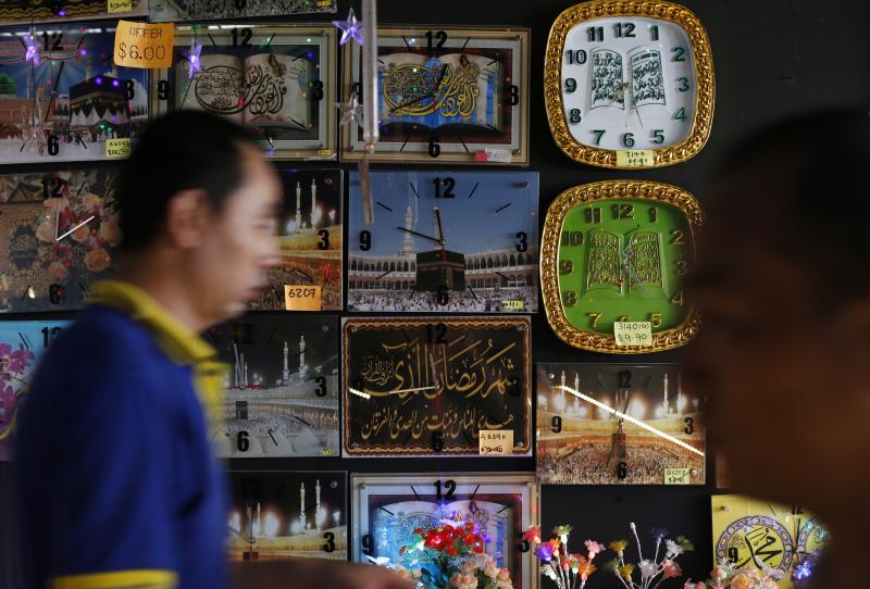 Edgar Su / Reuters People pass a stall selling clocks, depicting religious verses and pilgrims at the Hajj, at a Hari Raya bazaar, on the eve of Eid al-Fitr, in Singapore July 27, 2014.